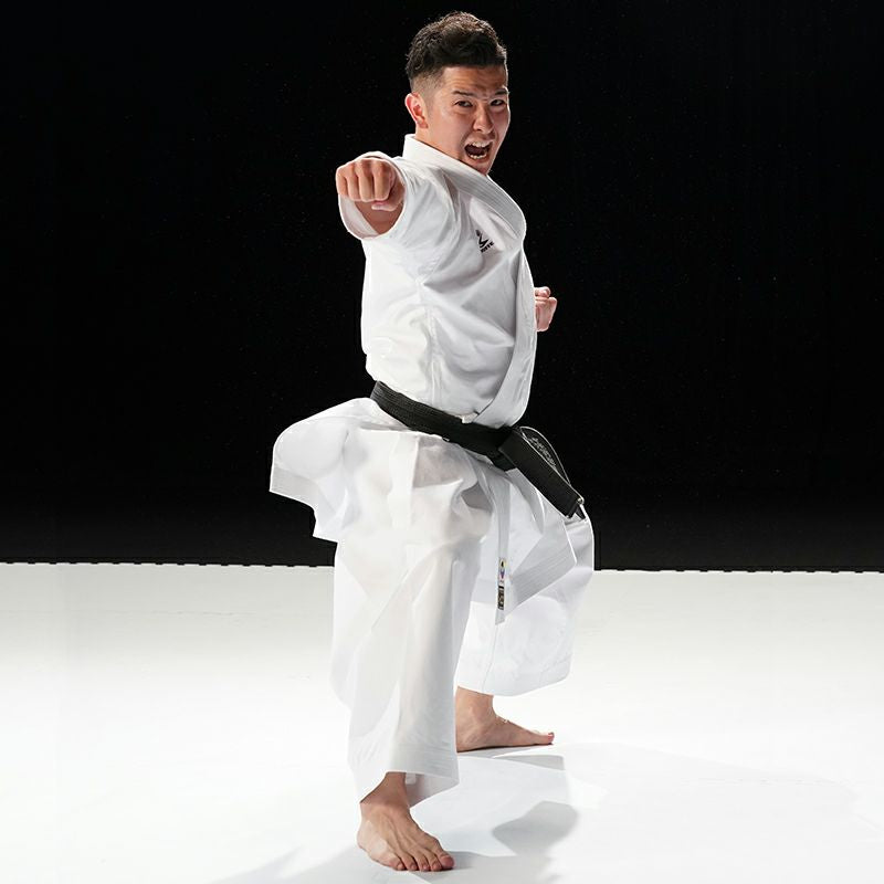 Person in a white martial arts uniform with a black belt performing a martial arts move on a white background