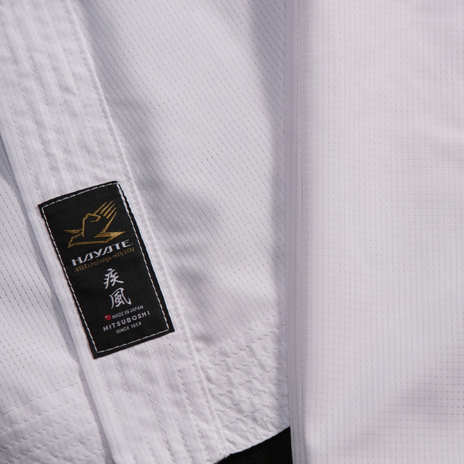 Close-up of a white martial arts uniform with a brand label on a black background
