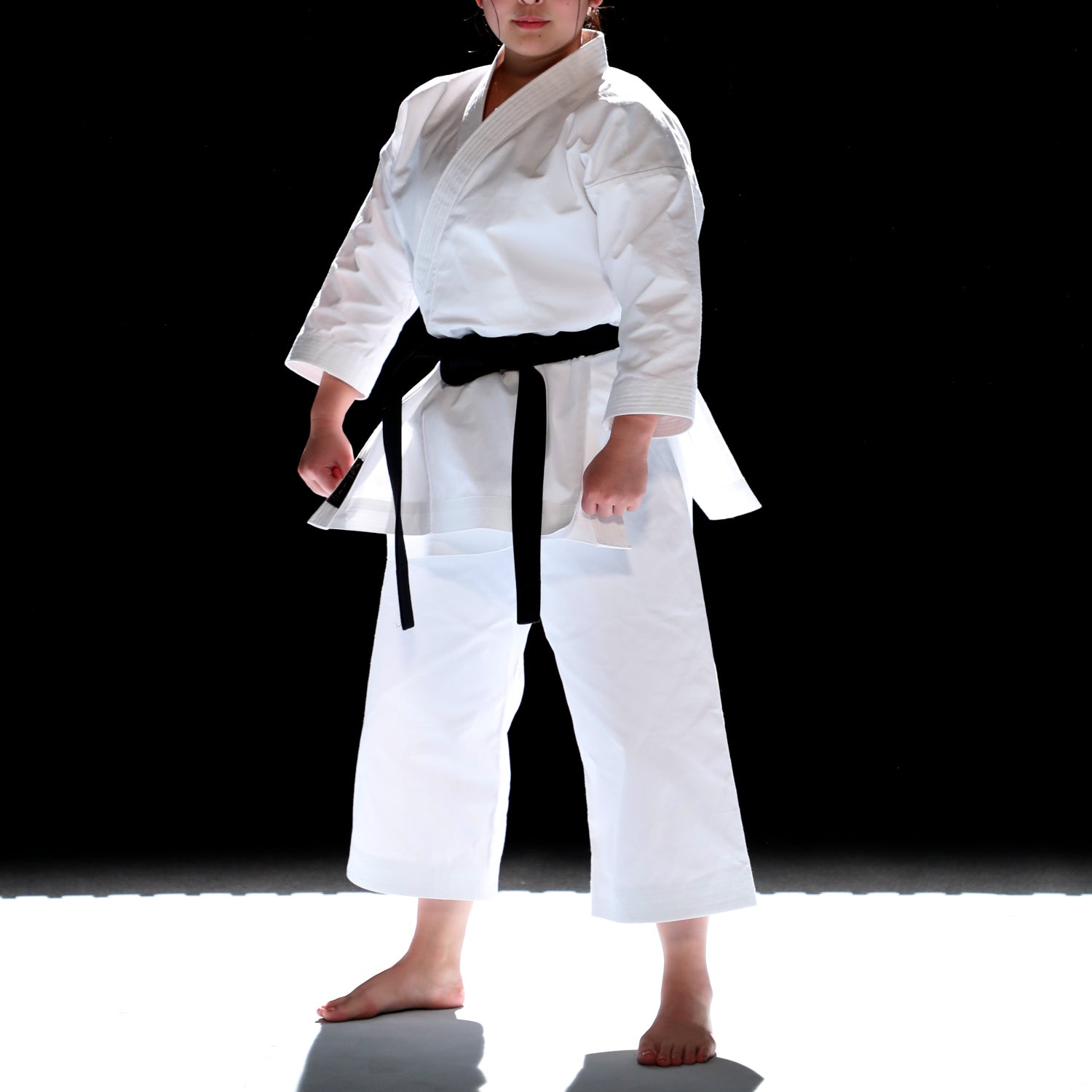 Person wearing a white martial arts uniform with a black belt on a white background