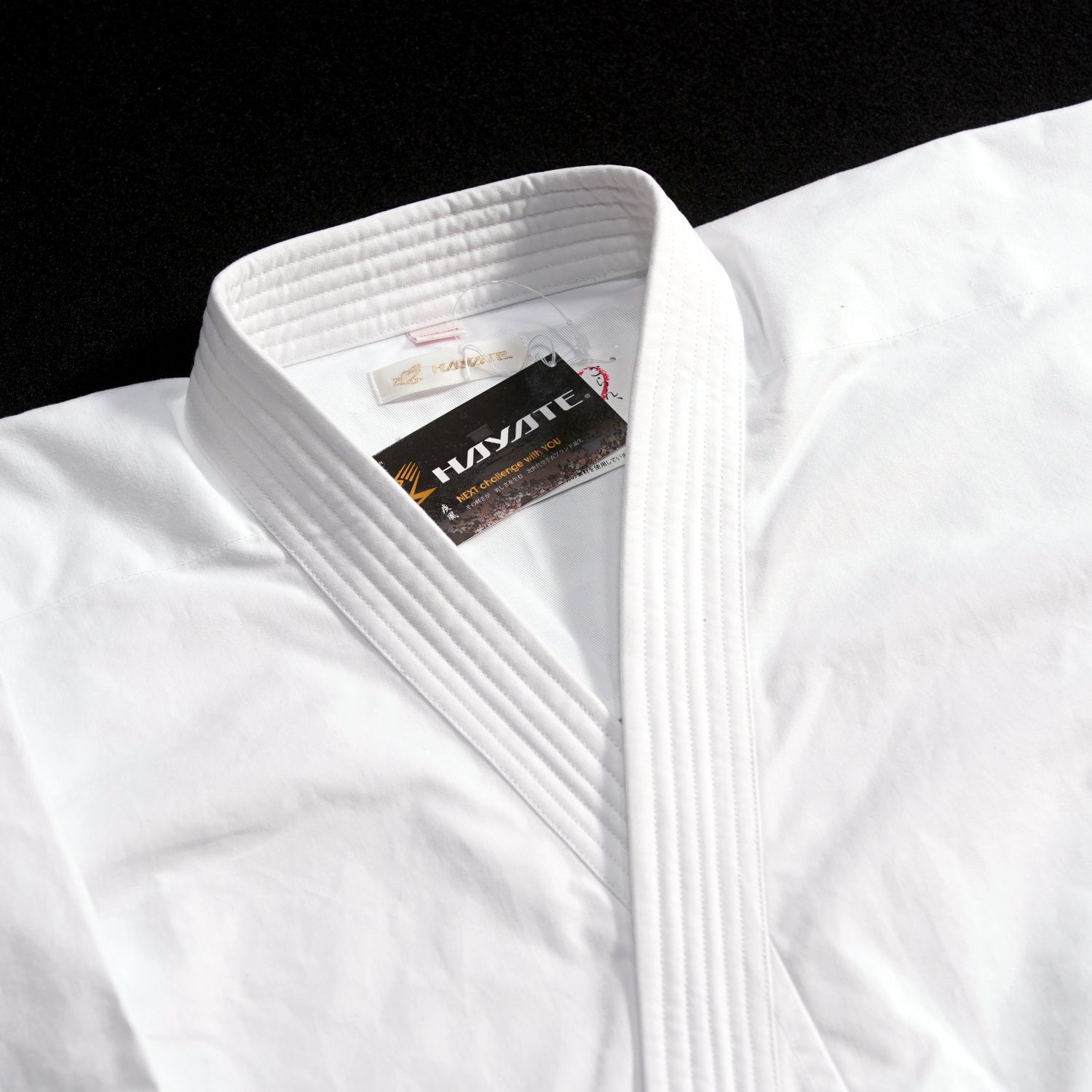 White martial arts gi with Hayate branding on a black background