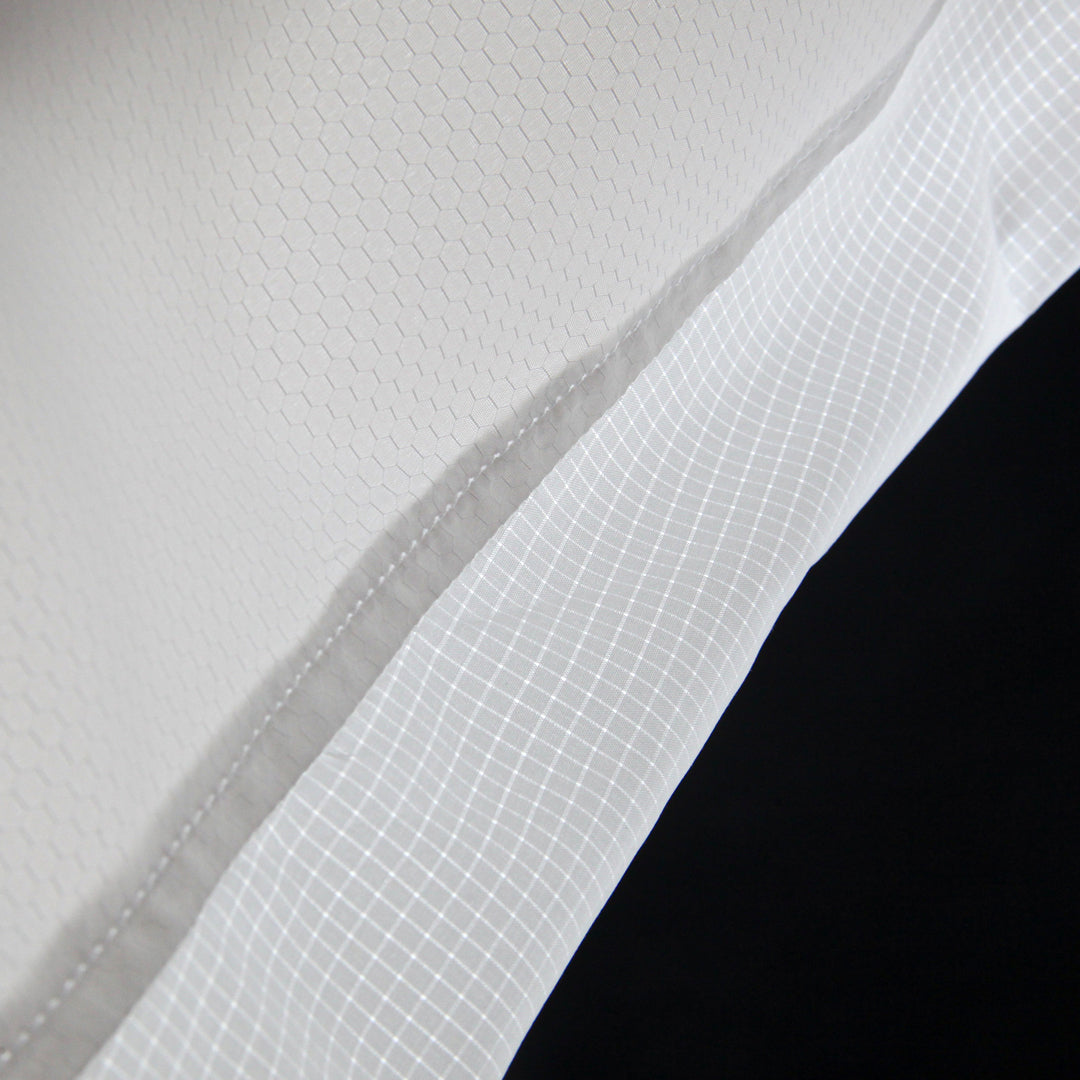 Close-up of a textured white fabric with a grid pattern on a light black background.