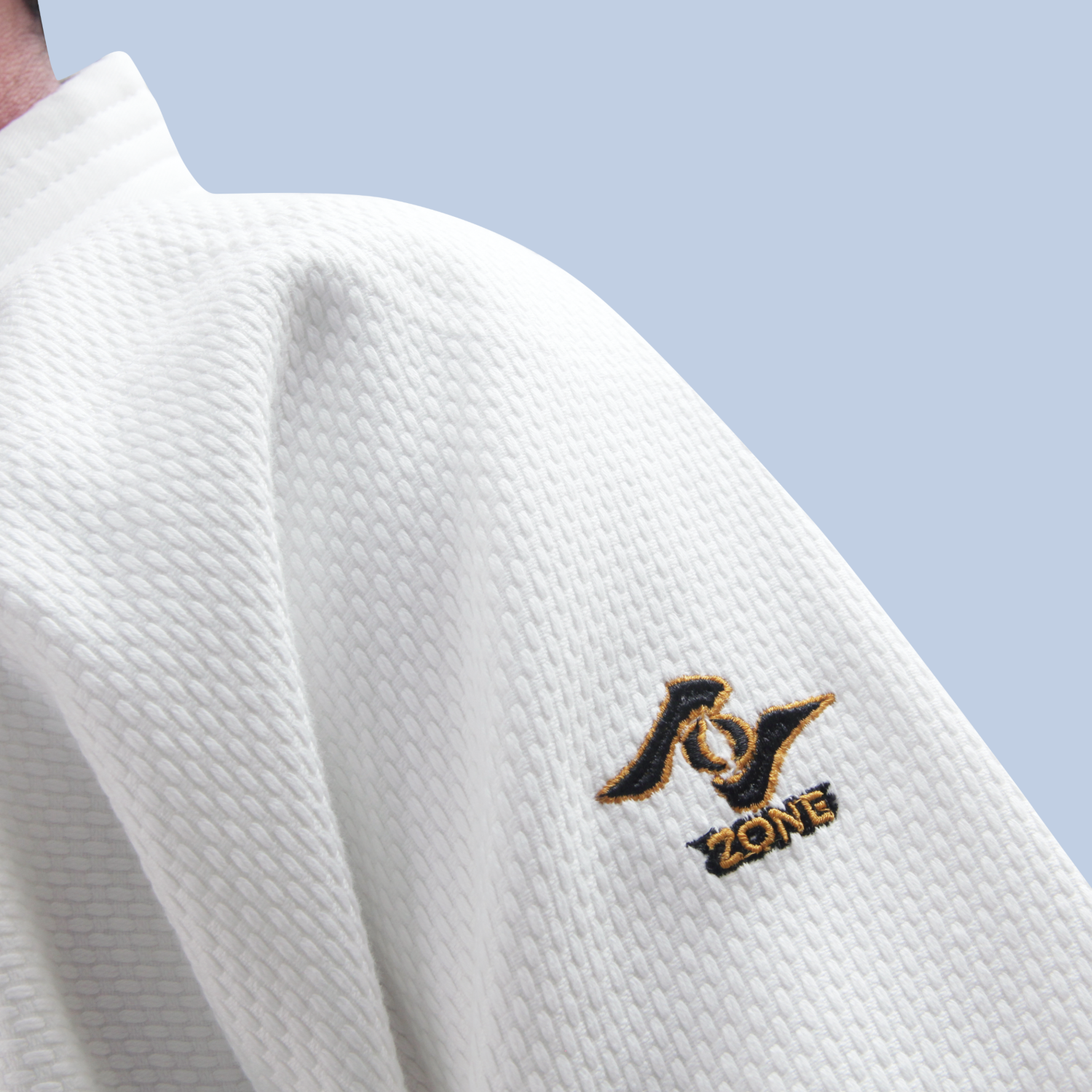 White martial arts uniform with embroidered Zone logo against a light blue background