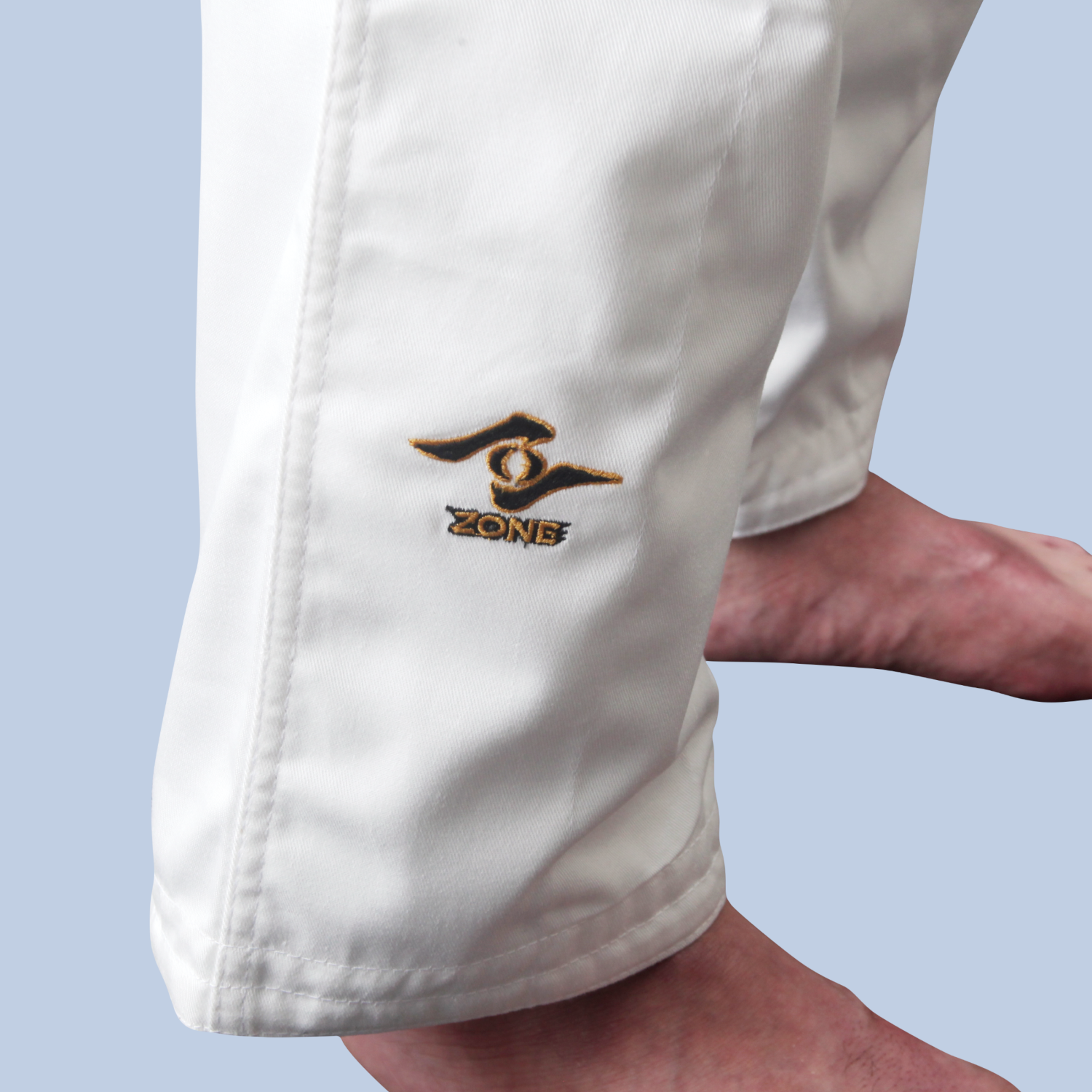 White pants with the Zone logo on the leg against a light blue background
