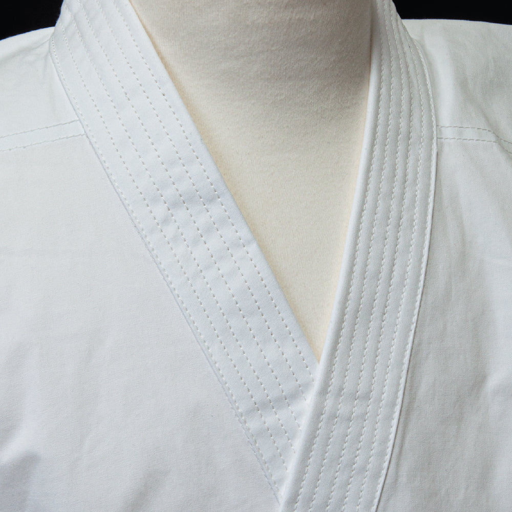 Close-up of a white martial arts gi with a belt on a black background
